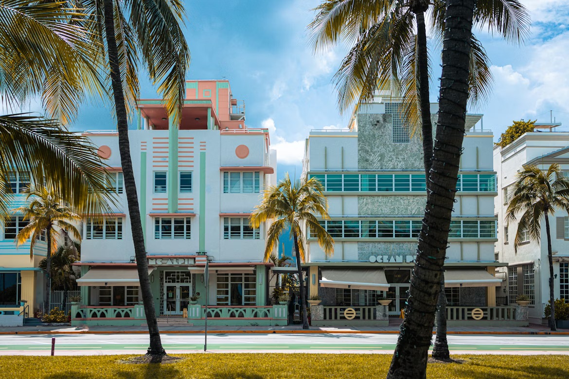 A view of the Pastel Deco buildings lined up with palm trees.