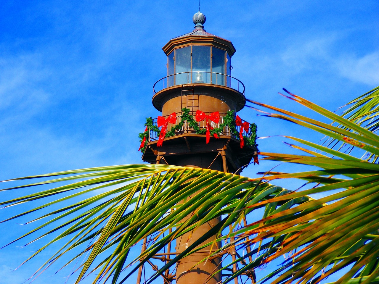 The historic Sanibel Island Lighthouse, decorated for the holidays, standing tall against a clear blue sky – a symbol of the island's maritime heritage.